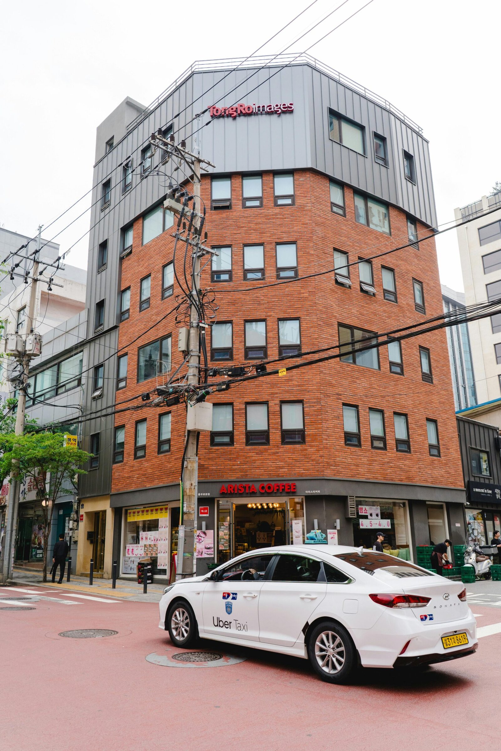 Street scene in Seoul featuring a red brick building and an Uber taxi.